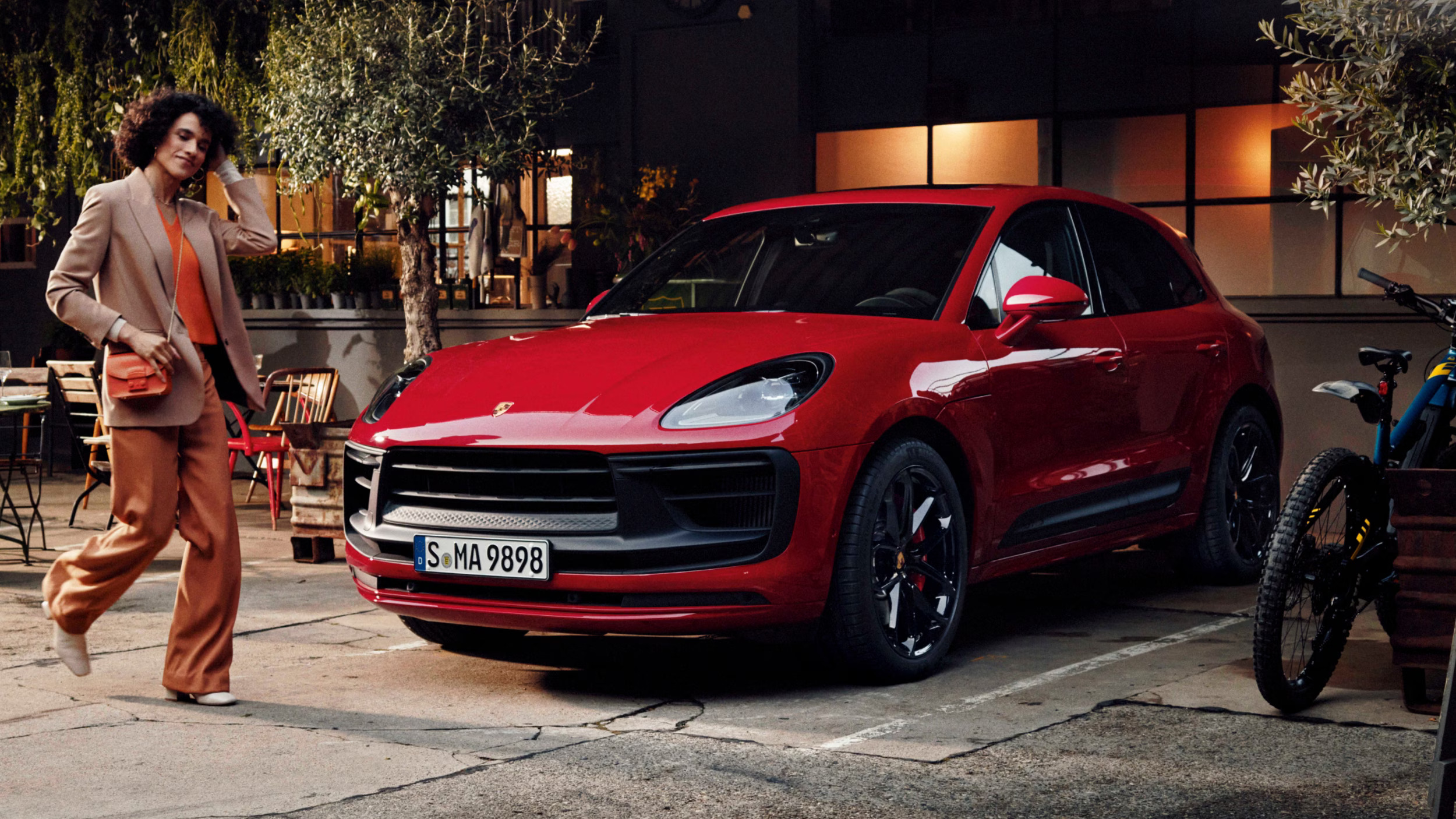 Red 2026 Porsche Macan GTS in motion showcasing its sleek design and aggressive front profile.