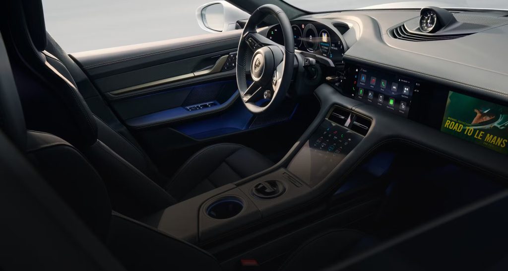 Porsche Taycan driving through a forest road illuminated by golden autumn sunlight.