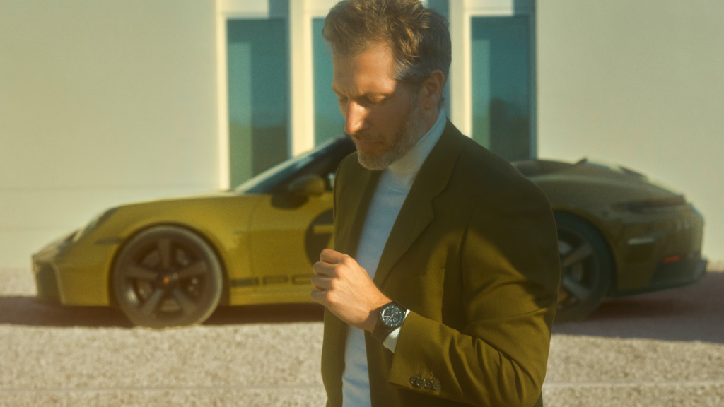 Mechanic inspecting Certified Pre-Owned Porsche 911 in dealership service bay.