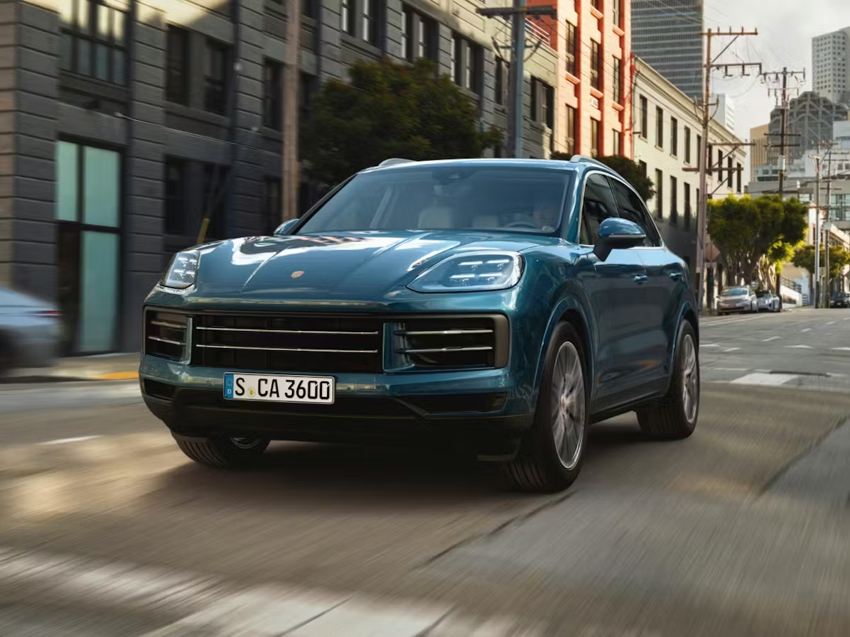 Blue Porsche Cayenne driving through a city street, showing why the Porsche Cayenne continues to define the luxury performance SUV.