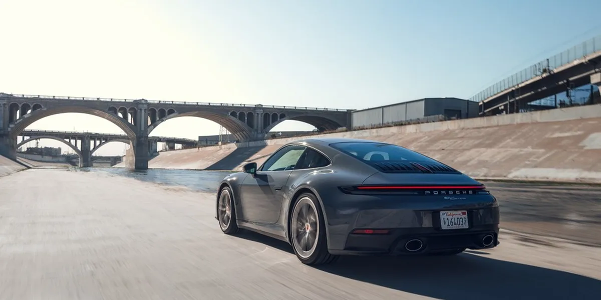 2026 Porsche 911 Carrera rear driving view under bridge by waterway