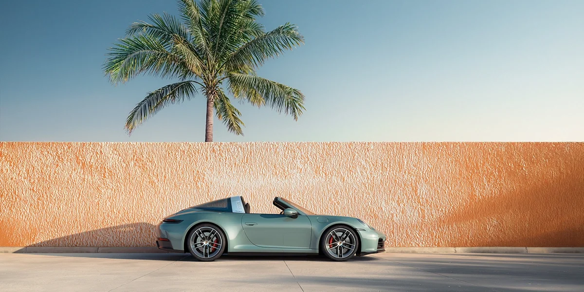 Side profile of 2026 Porsche 911 Carrera 4S Cabriolet in Ice Grey Metallic against a modern coastal backdrop, capturing classic 911 proportions and elegance.