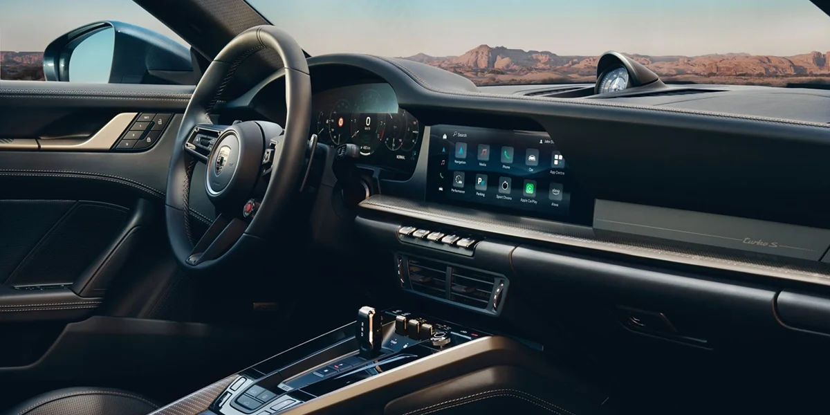 Driver-focused interior of the 2026 Porsche 911 Turbo S with digital cockpit and large infotainment screen.
