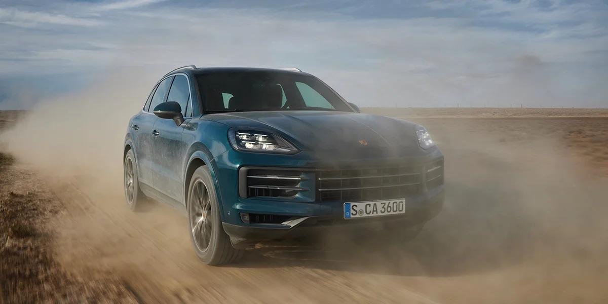 2026 Porsche Cayenne kicking up dust while driving fast off-road.