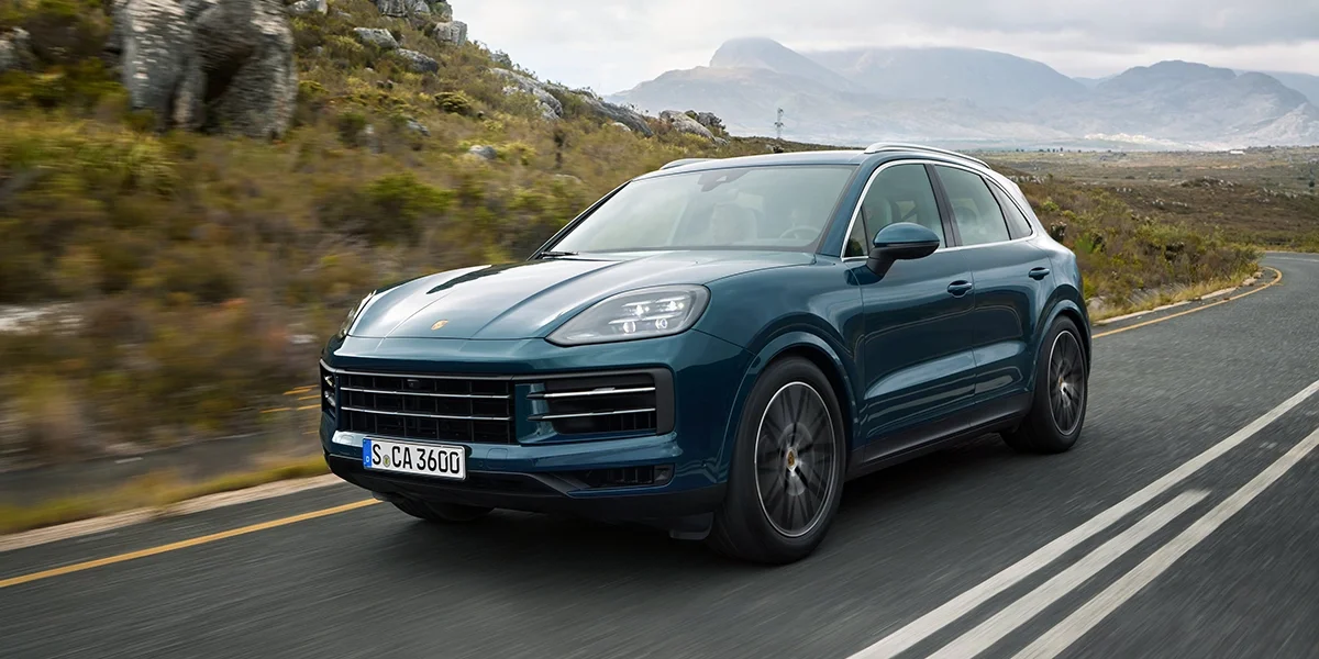 2026 Porsche Cayenne driving on a curved mountain road with scenic background.