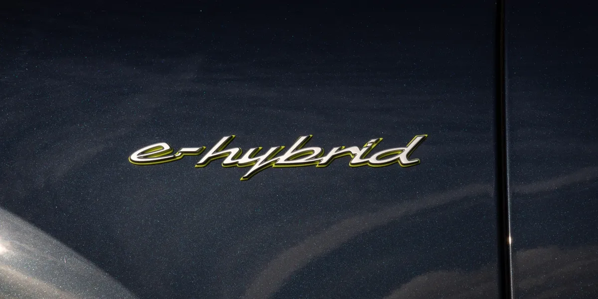 Side profile of the 2026 Porsche Cayenne with red Porsche livery parked by the sea