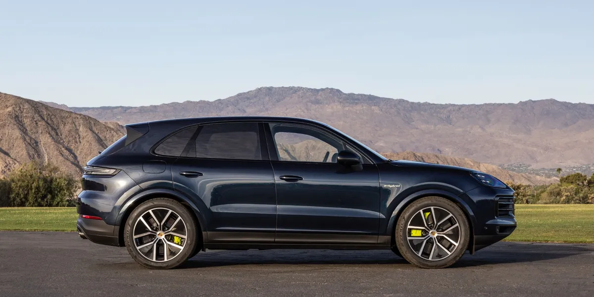 Side profile of the Porsche Cayenne E-Hybrid parked with mountains in the backdrop.