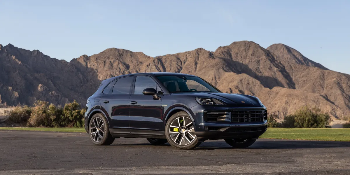 Front view of a Porsche Cayenne E-Hybrid driving through a scenic desert road.