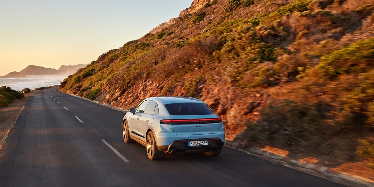 Rear three-quarter view of Porsche Macan T parked by waterfront with cityscape view