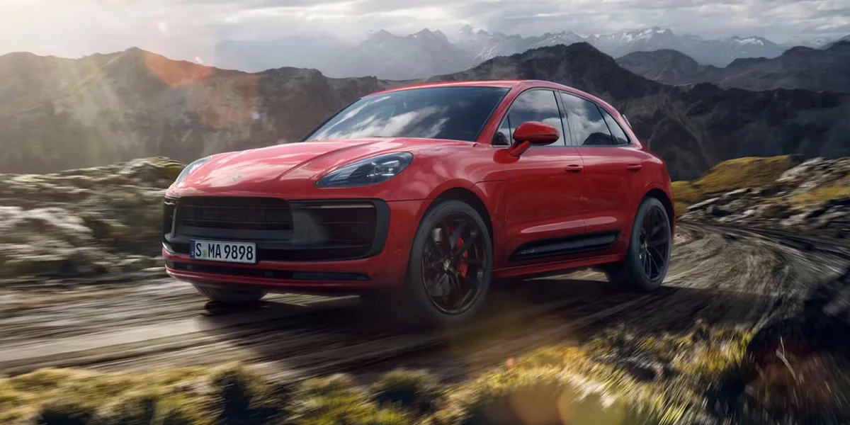 Red Porsche Macan GTS speeding along rugged mountain roads, demonstrating superb performance and handling.