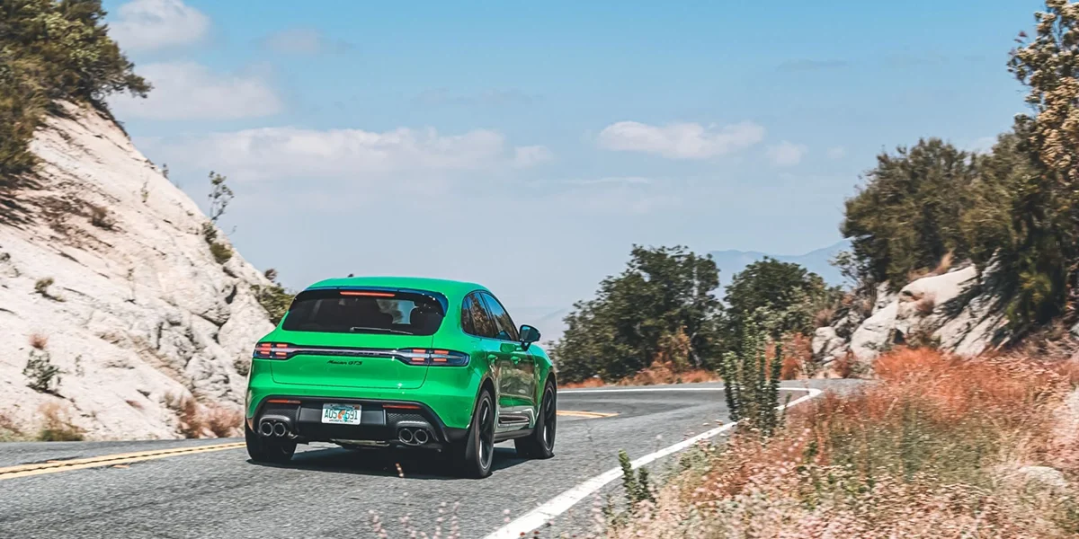 Rear view of Porsche Macan GTS in Python Green, highlighting quad exhaust system and sporty SUV stance.
