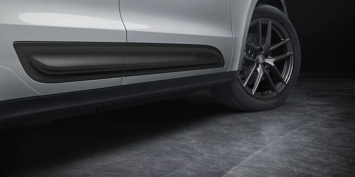 Close-up of Porsche Macan T side skirt and black alloy wheels under studio lighting