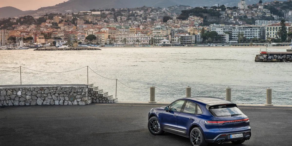 Rear three-quarter view of Porsche Macan T parked by waterfront with cityscape view