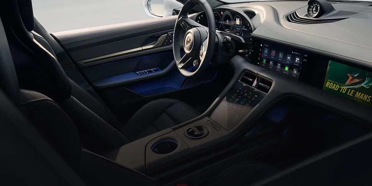 Porsche Taycan driving along a winding coastal road, showcasing balanced handling and electric agility.