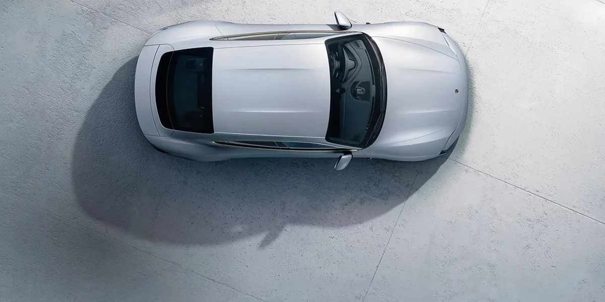 Low-angle front view of Porsche Taycan, LED headlights illuminated, highlighting sleek electric design.