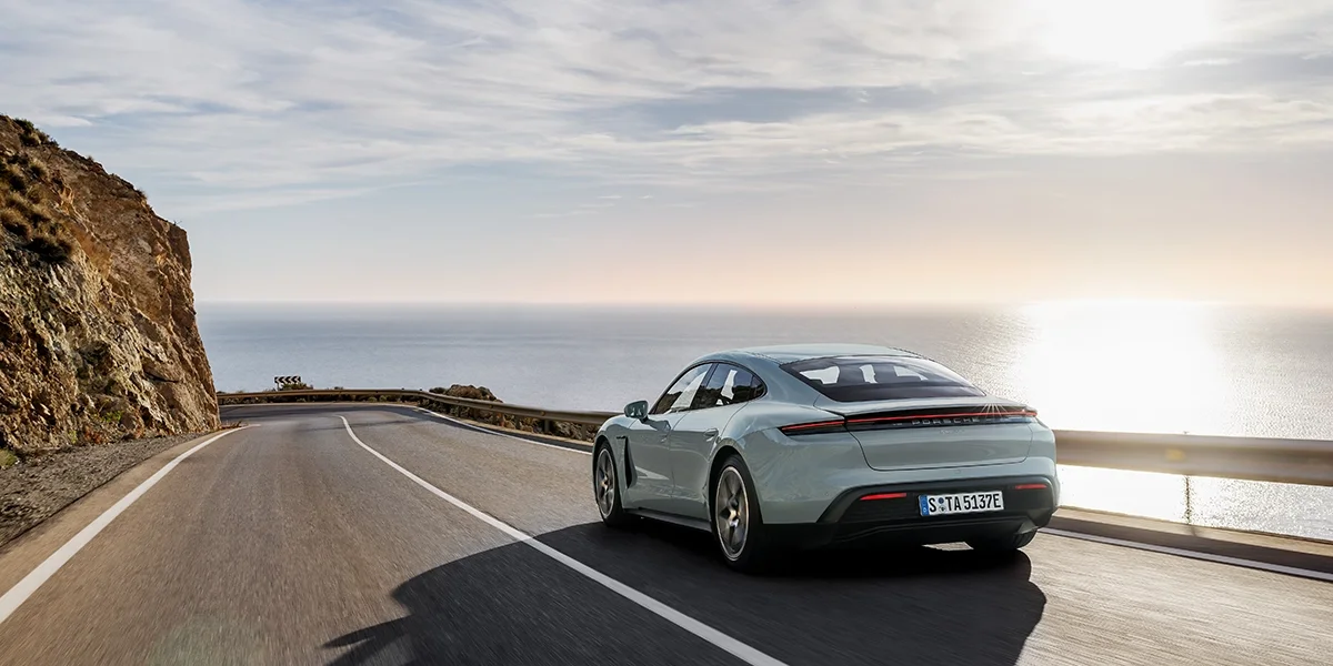 Overhead top view of the Porsche Taycan, emphasizing clean aerodynamic design lines and panoramic roof.