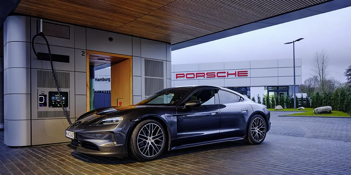 Porsche Taycan driver-focused cockpit with multi-display setup, navigation screen, and Alcantara steering wheel.