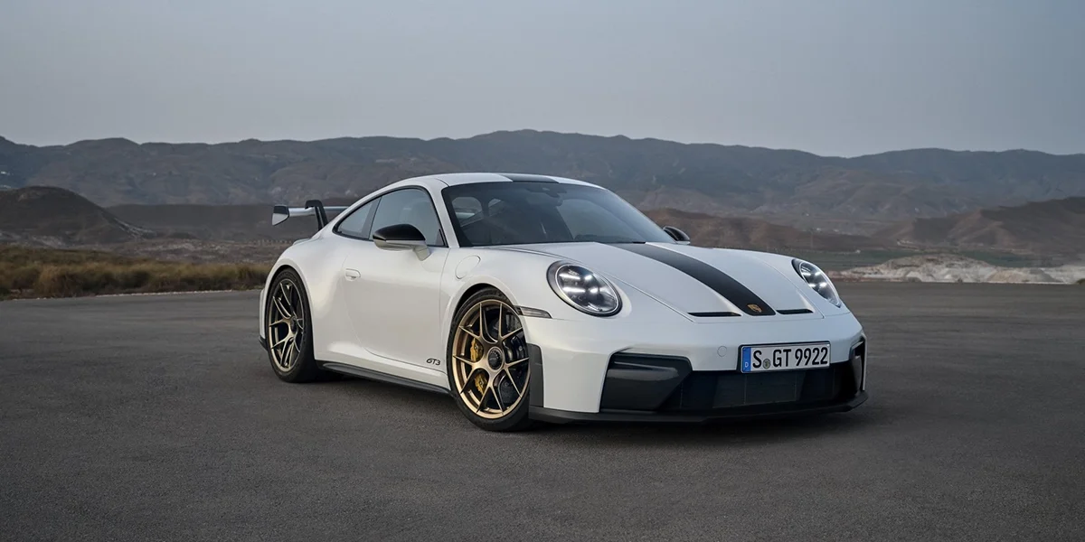 Porsche 911 GT3 driving on track, front three-quarter view with motion blur.
