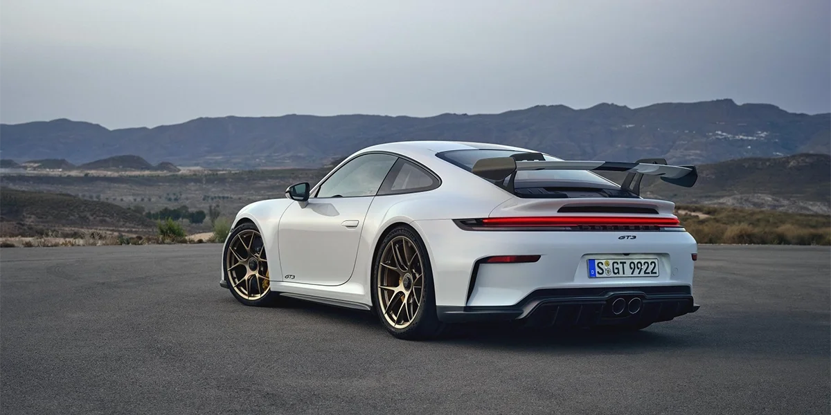 Porsche 911 GT3 front angle shot at sunset on race track, dramatic sky.