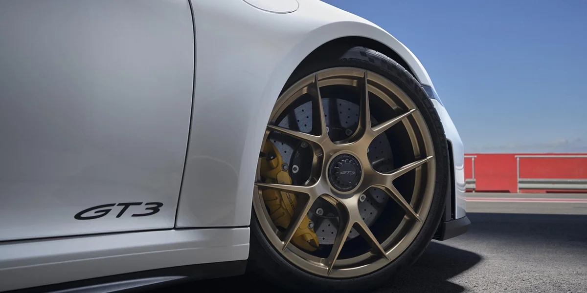 Interior view of Porsche 911 GT3, steering wheel, digital cluster, and manual shifter visible.