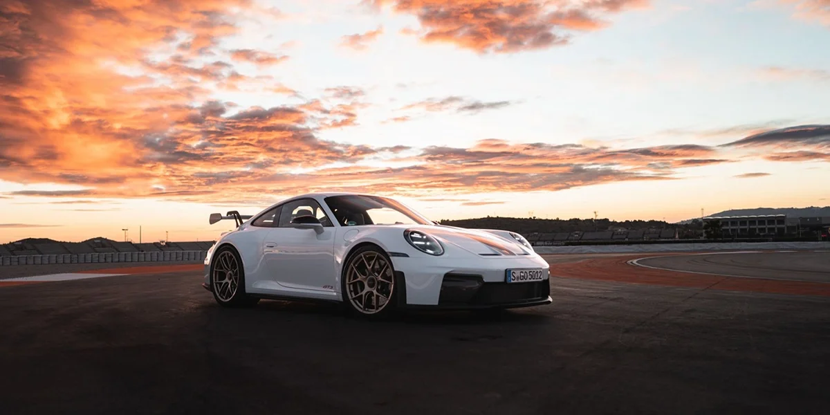 Porsche 911 GT3 front view at sunrise on track, aggressive styling highlighted.