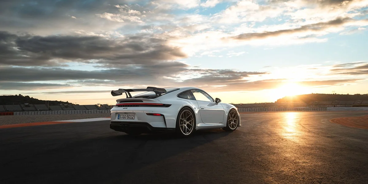 Porsche 911 GT3 front three-quarter view parked on open asphalt with mountains in background. 