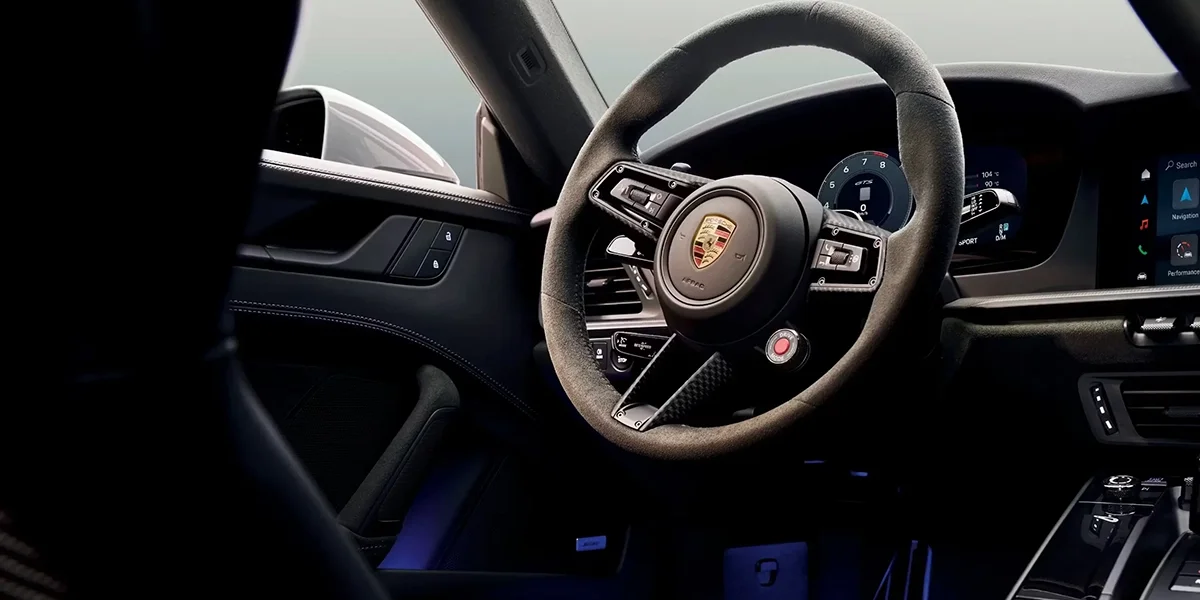 Porsche 911 driver-focused digital cockpit with steering wheel controls and central display.