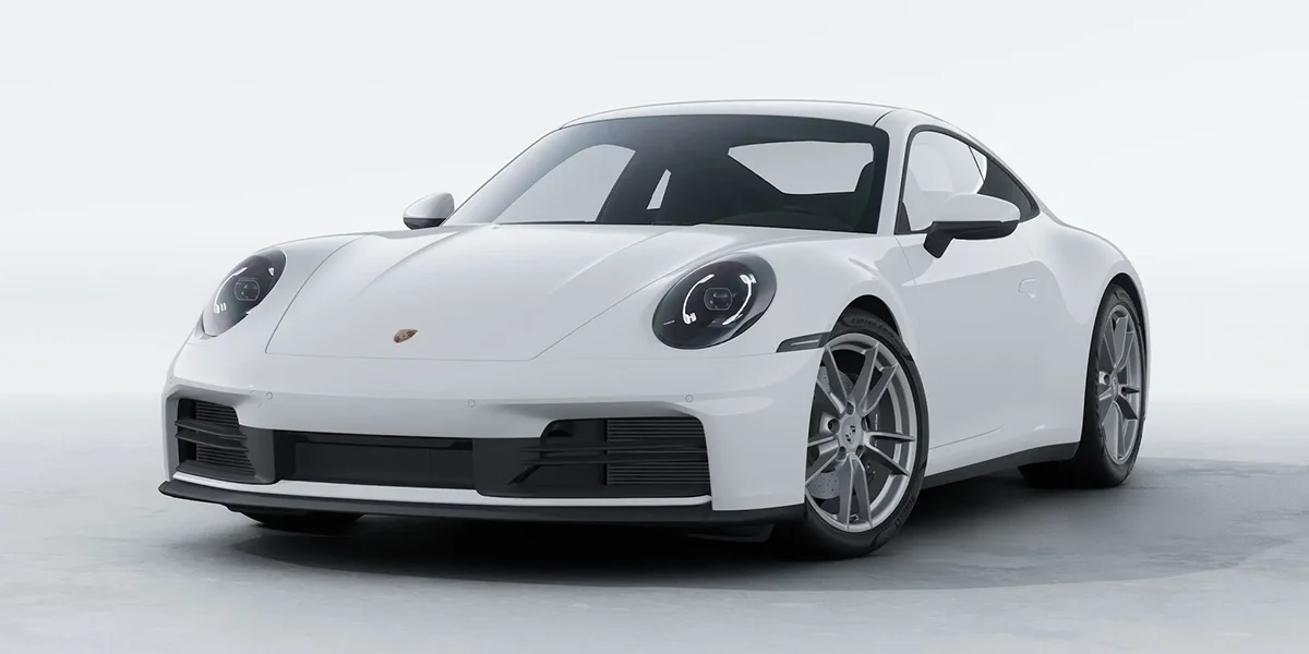 White Porsche 911 coupe photographed from a front three-quarter angle in a studio.