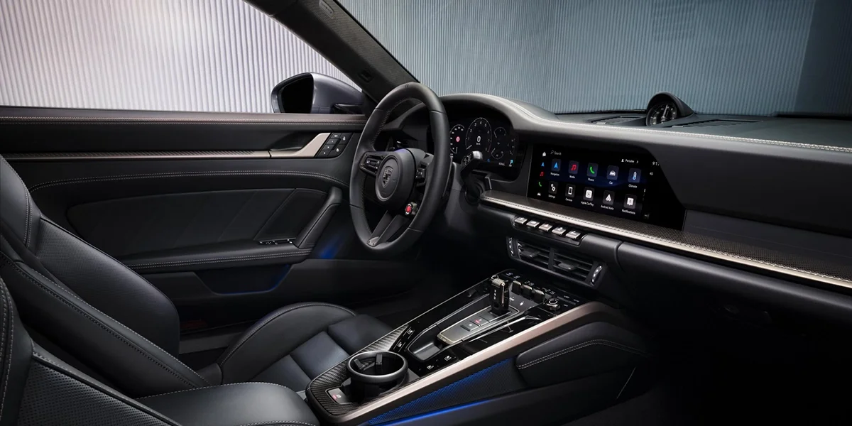 Rear three-quarter view of Porsche 911 Turbo S Cabriolet in studio lighting, red convertible roof folded.