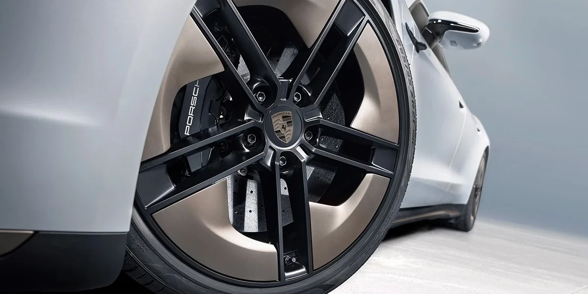 Porsche Taycan wheel and brake close-up with Porsche-branded caliper.