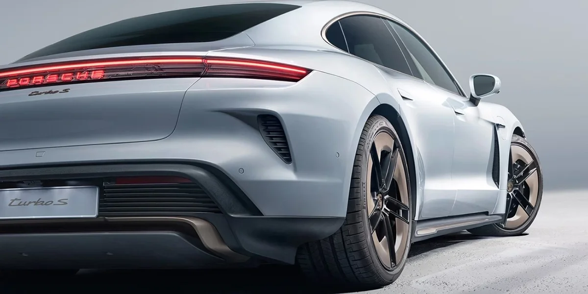 Porsche Taycan rear three-quarter view highlighting wide stance and rear light bar.