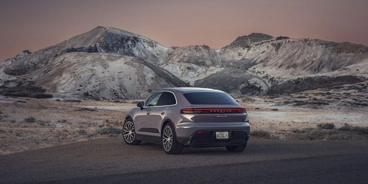 Rear view of the 2024 Porsche Macan 4S SUV with LED light bar, set against rugged mountain scenery.