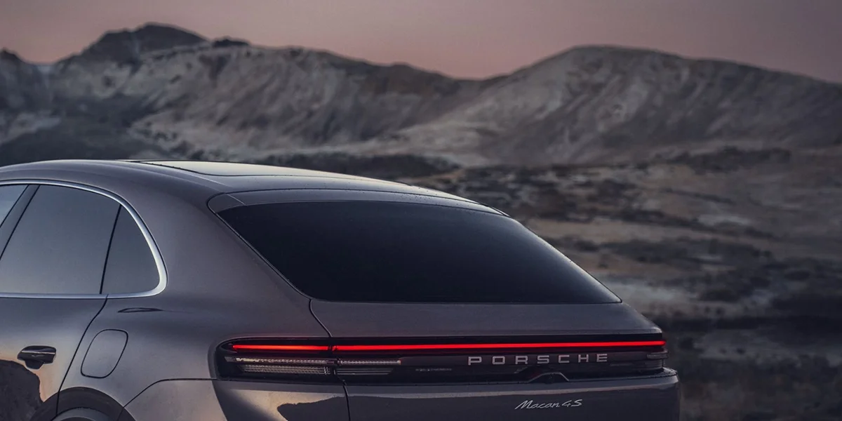 Porsche Macan 4S driving along a mountain road, demonstrating dynamic performance and agility.