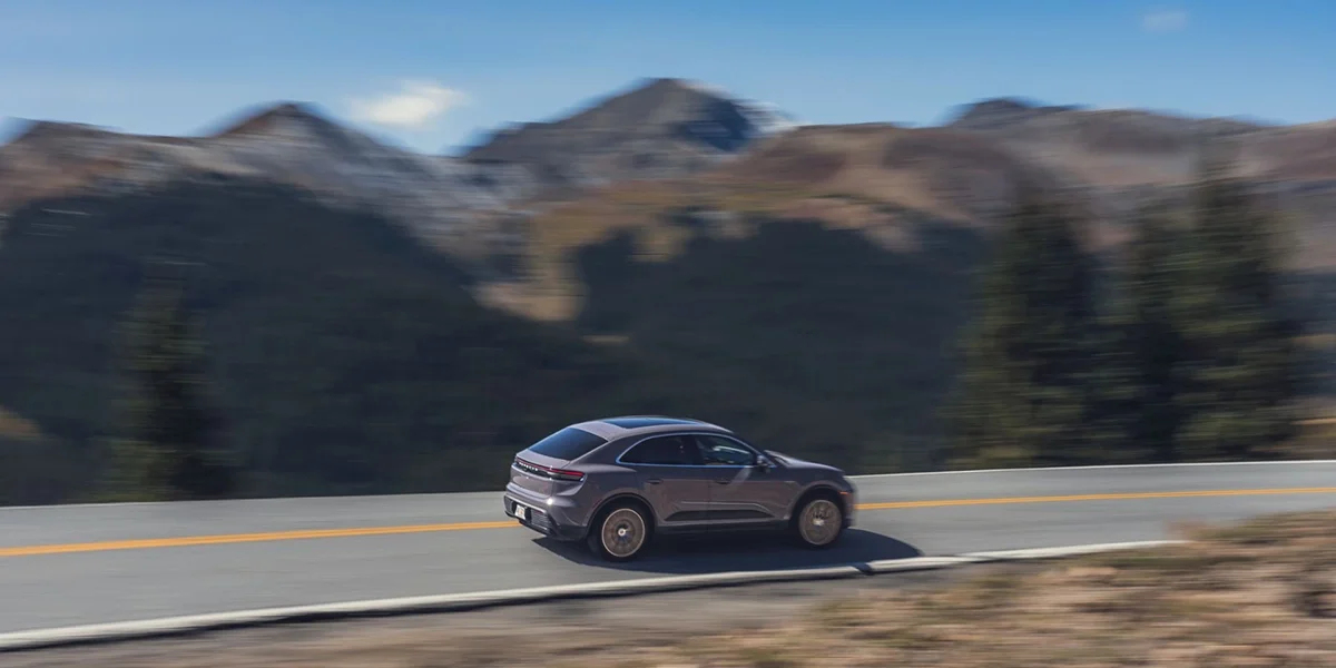 Porsche Macan 4S driving along a mountain road, demonstrating dynamic performance and agility.