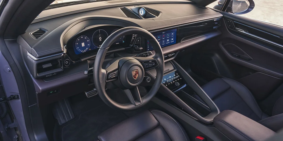 Interior cockpit of the 2024 Porsche Macan 4S featuring digital driver display, touchscreen infotainment, and sport steering wheel.