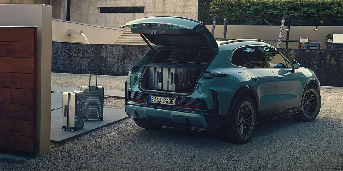 Porsche Cayenne with open trunk loaded with luggage, showing spacious rear cargo area.