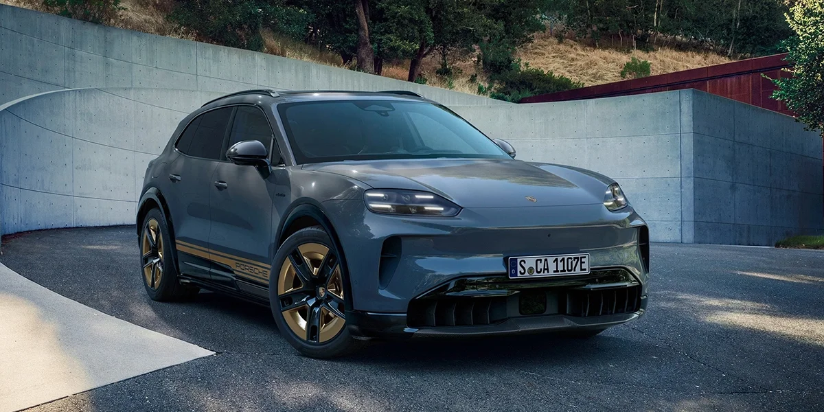 Front view of the Porsche Macan Electric driving on a coastal road.