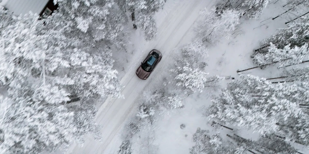 Porsche Taycan side mirror close-up reflecting sunset tones across its metallic paint.