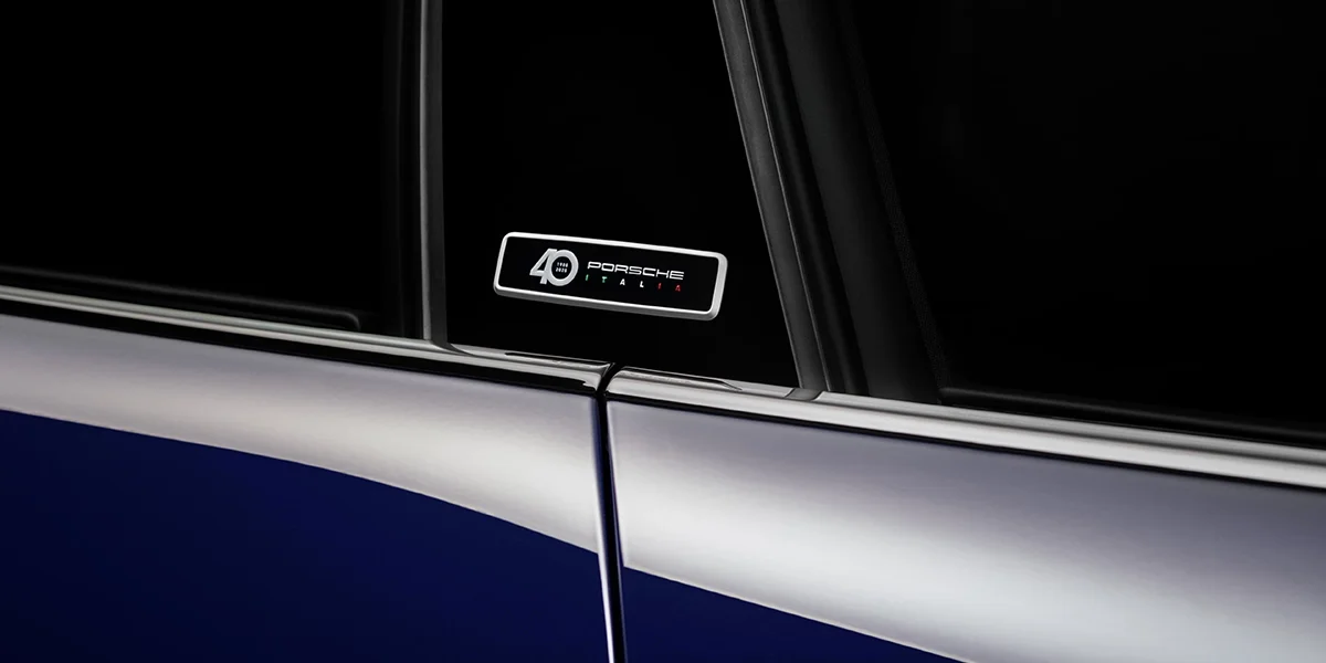 Close-up of Porsche crest emblem on the hood, highlighted under soft winter sunlight.