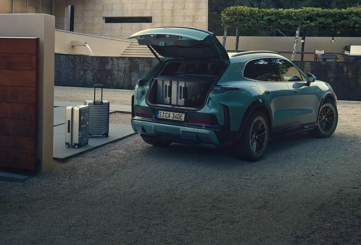 Green 2027 Porsche Cayenne Electric with its rear cargo area open and loaded with luggage.