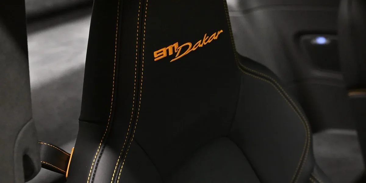 Close-up of Porsche 911 Dakar seat embroidery with orange stitching and black leather finish