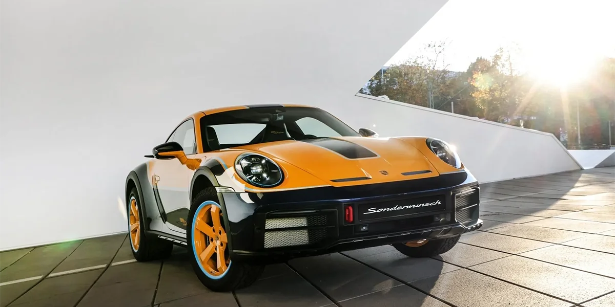 Porsche 911 Dakar parked indoors with raised suspension, yellow wheels, and rugged off-road design