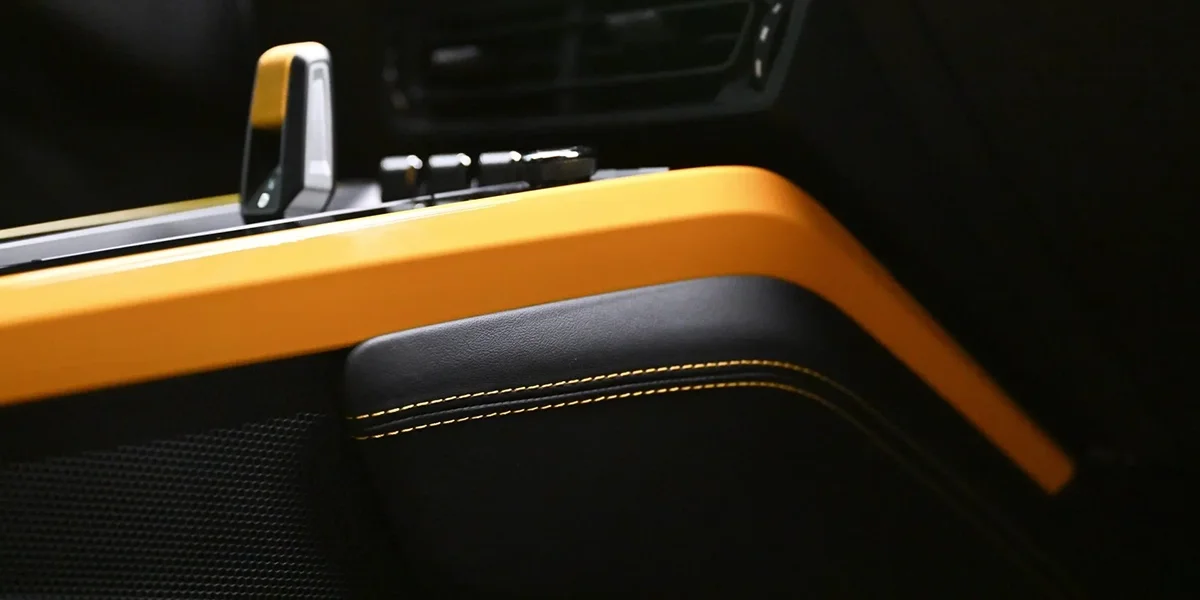 Interior close-up of Porsche 911 Dakar showing yellow trim and contrast stitching on black cabin surfaces